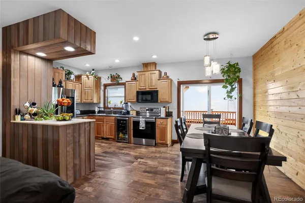 a kitchen with stainless steel appliances kitchen island granite countertop a table chairs and a refrigerator