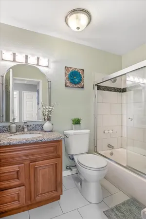 a bathroom with a granite countertop sink toilet a large mirror a shower and a bathtub
