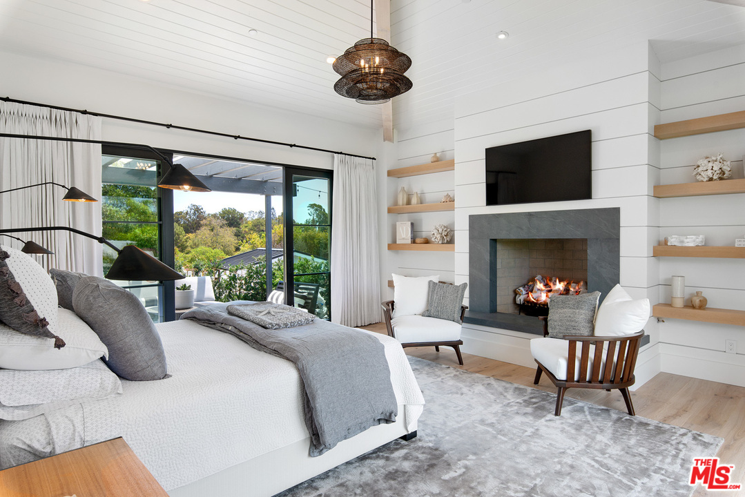 6530 Zuma View Place Malibu, CA 90265 - Photo 11 of 31 a bedroom with a large bed and a fireplace