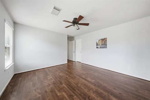 a view of a room with wooden floor and a ceiling fan