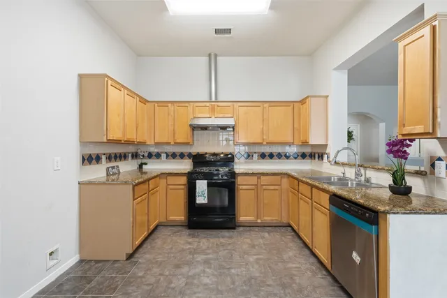 a kitchen with stainless steel appliances granite countertop a sink stove cabinets and a refrigerator
