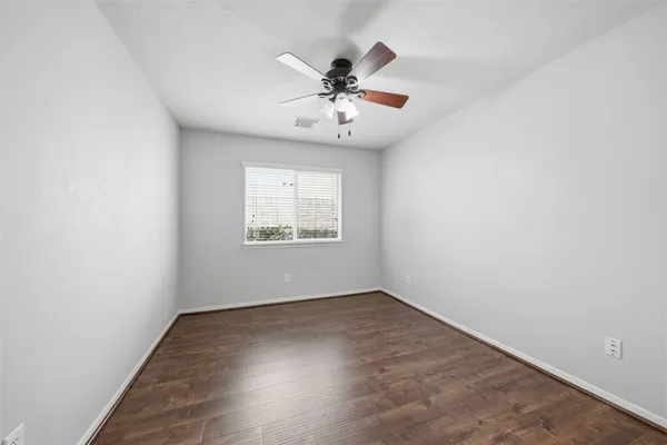 an empty room with wooden floor chandelier and windows