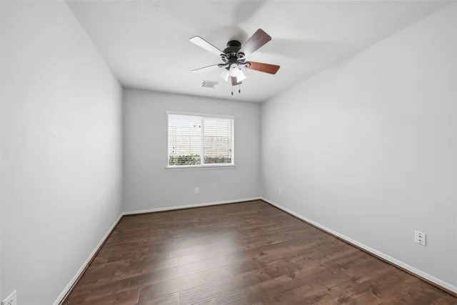 an empty room with wooden floor chandelier and windows