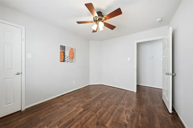 an empty room with wooden floor and ceiling fan