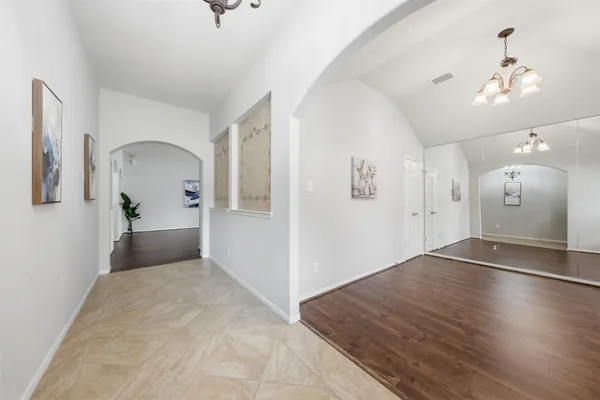 a view of a hallway with wooden floor and a chandelier