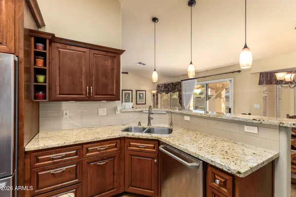 a kitchen with stainless steel appliances granite countertop a sink a stove and a wooden cabinets