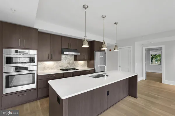 a kitchen with kitchen island a sink stainless steel appliances and wooden floor