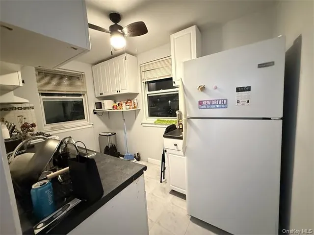 a kitchen with stainless steel appliances a refrigerator a microwave a stove and white cabinets