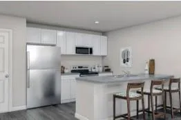 a kitchen with stainless steel appliances granite countertop a refrigerator a stove a sink a microwave a dining table and chairs