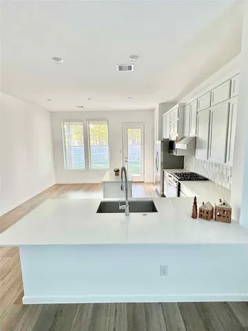 a kitchen with kitchen island a sink a stove and white cabinets