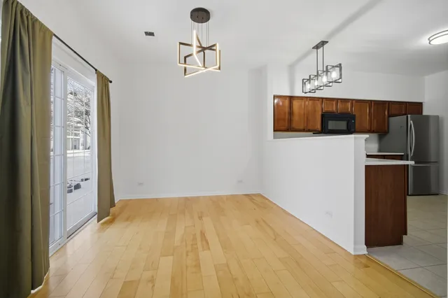 a view of kitchen with stainless steel appliances wooden floor and living room view