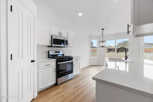 a kitchen with stainless steel appliances granite countertop a stove top oven a sink and a refrigerator