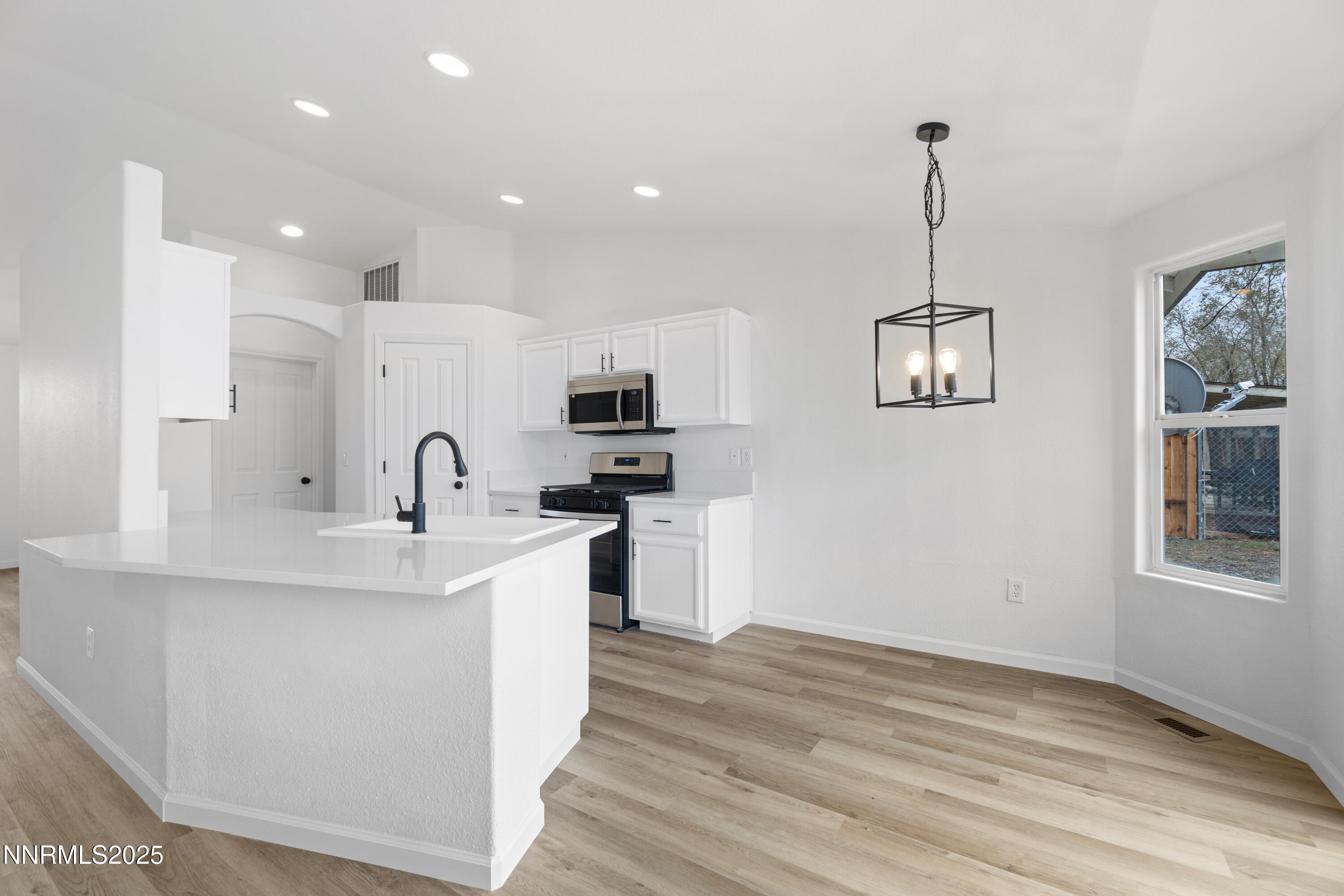 123 Shadow Mountain Drive Fernley, NV 89408 - Photo 9 of 28 a kitchen with stainless steel appliances kitchen island a refrigerator a sink dishwasher a stove and white cabinets with wooden floor