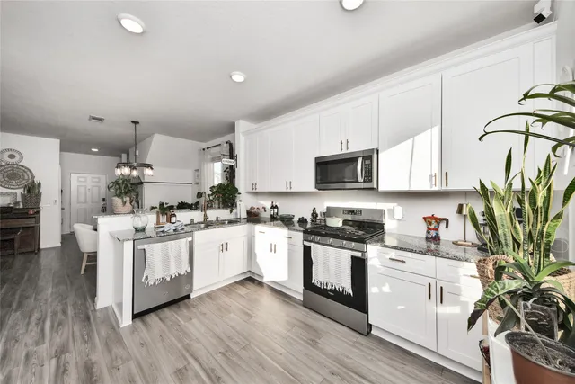 a kitchen with stove a sink and white cabinets with wooden floor