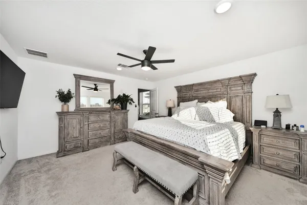 a bedroom with a bed a dresser and a flat screen tv