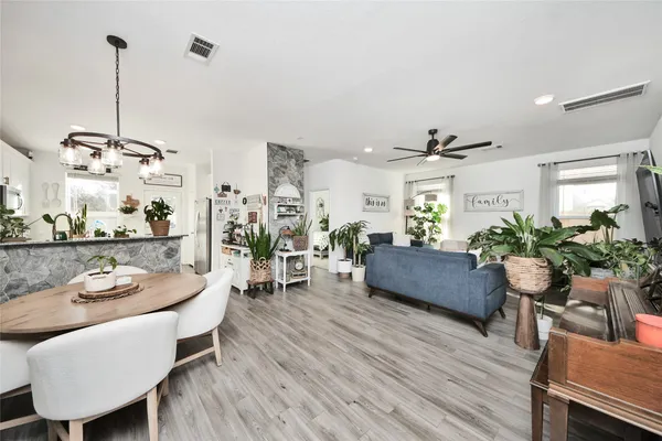 a living room with furniture kitchen view and a wooden floor