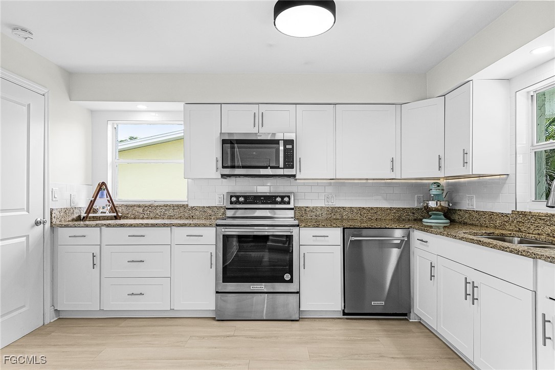 1060 Cooper Drive Naples, FL 34103 - Photo 11 of 33 a kitchen with stainless steel appliances granite countertop a stove a sink and a microwave