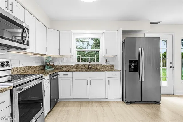 a kitchen with stainless steel appliances granite countertop a refrigerator stove and sink