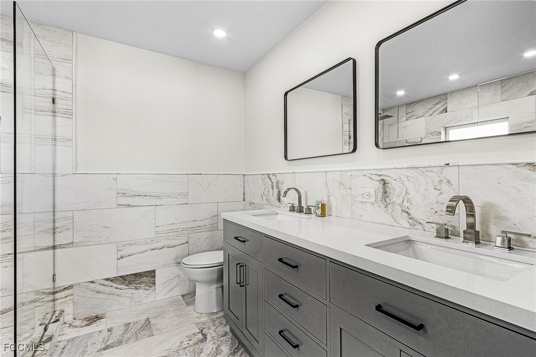 1060 Cooper Drive Naples, FL 34103 - Photo 26 of 33 a bathroom with a granite countertop sink a toilet and a mirror