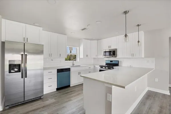 a kitchen with cabinets stainless steel appliances a sink and wooden floor