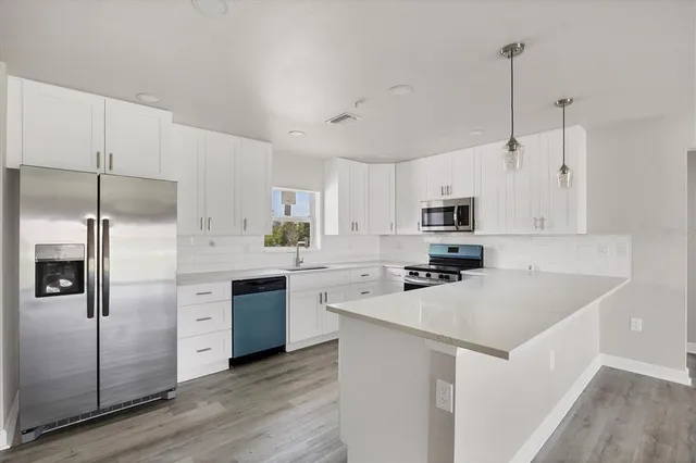 a kitchen with cabinets stainless steel appliances a sink and wooden floor