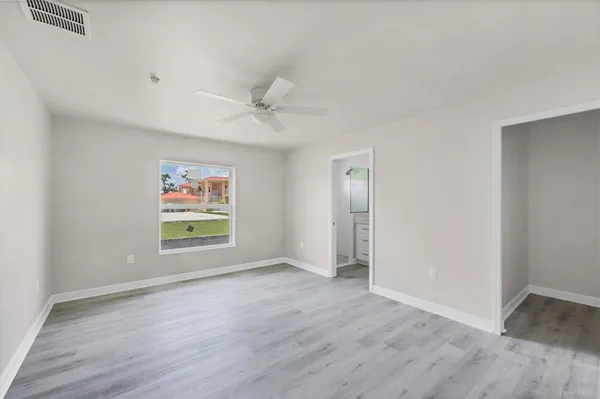 an empty room with wooden floor fan and windows