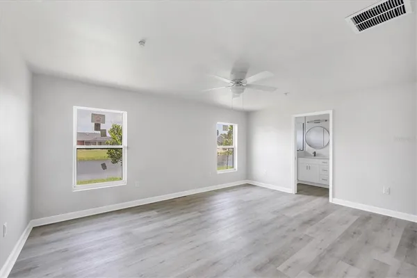 an empty room with windows and ceiling fan