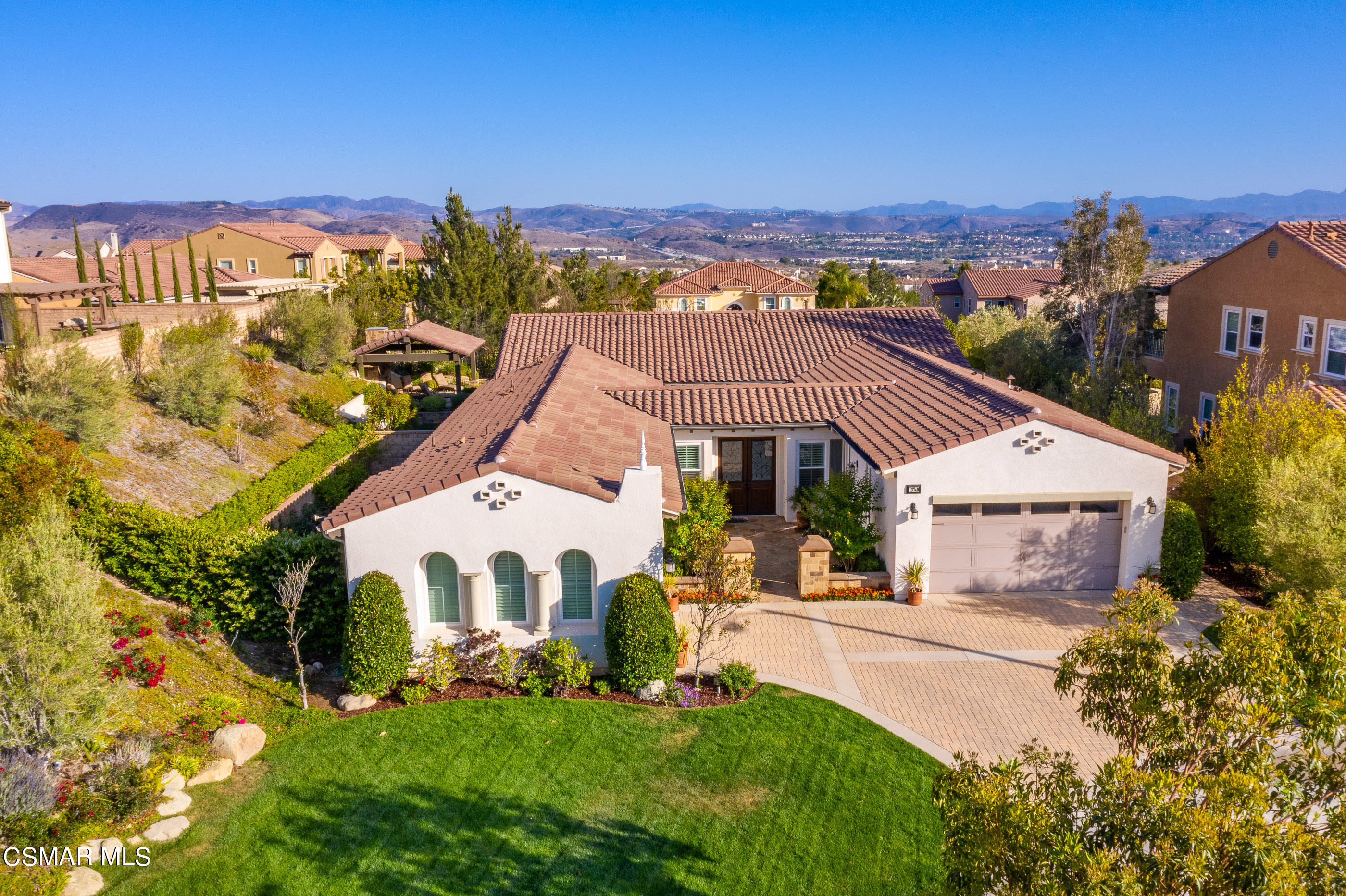 a view of a white house with a big yard plants and large trees