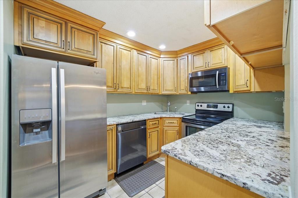2666 Pine Ridge Way North, Unit C2 Palm Harbor, FL 34684 - Photo 18 of 74 a kitchen with stainless steel appliances granite countertop a refrigerator stove top oven a sink and dishwasher