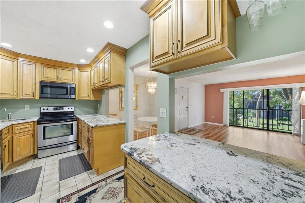 2666 Pine Ridge Way North, Unit C2 Palm Harbor, FL 34684 - Photo 19 of 74 a kitchen with stainless steel appliances granite countertop a stove a sink and a microwave