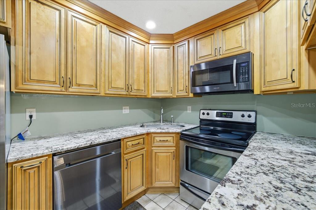 2666 Pine Ridge Way North, Unit C2 Palm Harbor, FL 34684 - Photo 22 of 74 a kitchen with stainless steel appliances granite countertop a stove microwave and cabinets