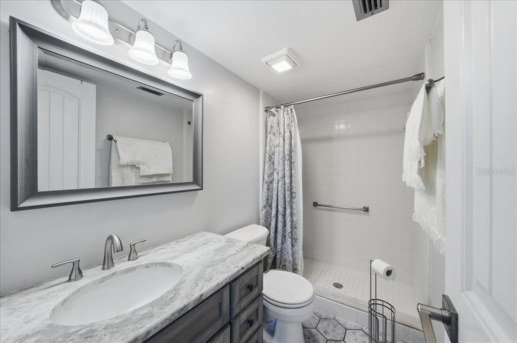 2666 Pine Ridge Way North, Unit C2 Palm Harbor, FL 34684 - Photo 33 of 74 a bathroom with a granite countertop sink toilet a mirror and shower