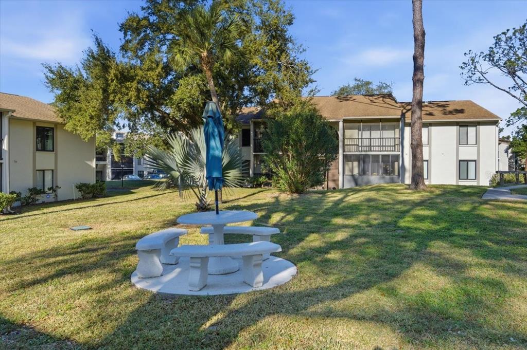 2666 Pine Ridge Way North, Unit C2 Palm Harbor, FL 34684 - Photo 48 of 74 a front view of a house with a yard table and chairs