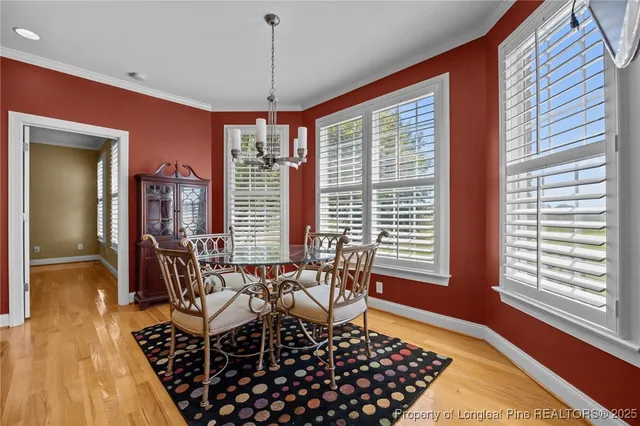 a dining room with wooden floor a chandelier and windows