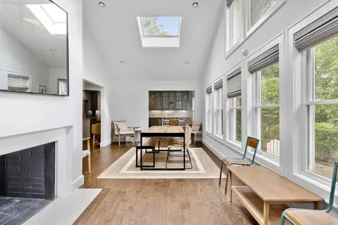 a living room with furniture a fireplace wooden floor and a large window