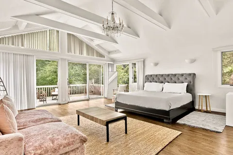 a spacious bedroom with a bed a table and large windows