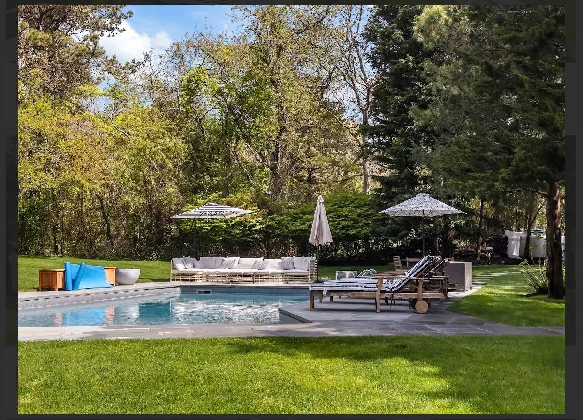 29 Petrel Road Southampton, NY 11968 - Photo 24 of 28 a view of a swimming pool with lawn chairs under an umbrella