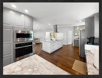 a kitchen with stainless steel appliances kitchen island granite countertop a refrigerator oven a stove with white cabinets
