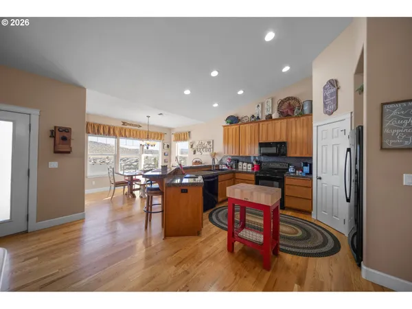 a kitchen with stainless steel appliances kitchen island granite countertop a table chairs and a refrigerator