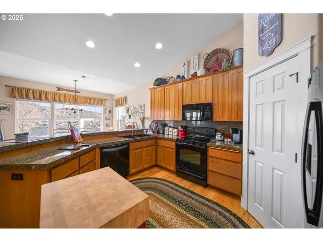 a kitchen with stainless steel appliances kitchen island granite countertop a sink stove and refrigerator