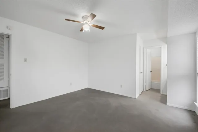 an empty room with a chandelier fan and windows