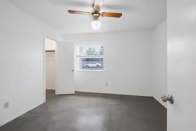 an empty room with a ceiling fan and a window
