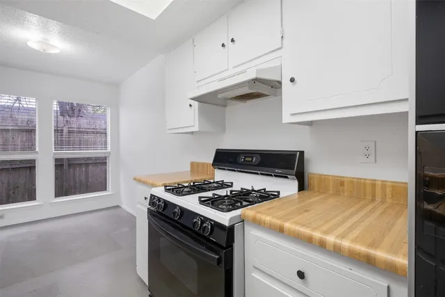 a kitchen with stainless steel appliances granite countertop a stove and a white cabinets