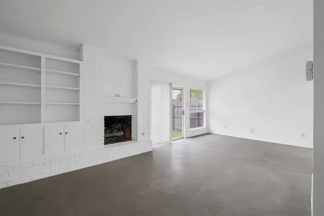 a view of an empty room with a fireplace and a window