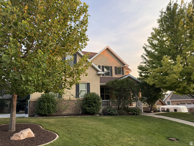 2388 East 850 South Springville, UT 84663 - Photo 52 of 58 Two-story residence featuring stucco and brick siding, a covered front porch, and mature trees