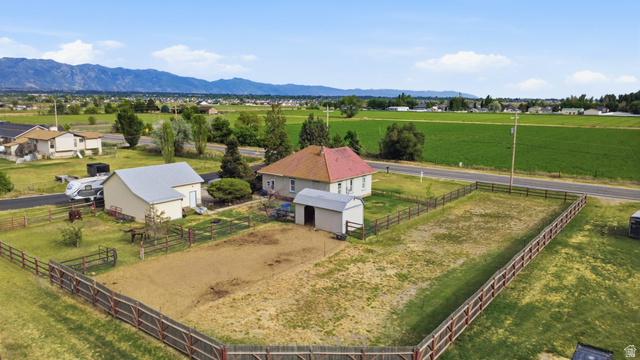 5264 West 5500th Street South Hooper, UT 84315 - Photo 33 of 38 Expansive property featuring a main residence with a red roof, a separate accessory building with a gray roof, a smaller shed, and fenced pasture areas