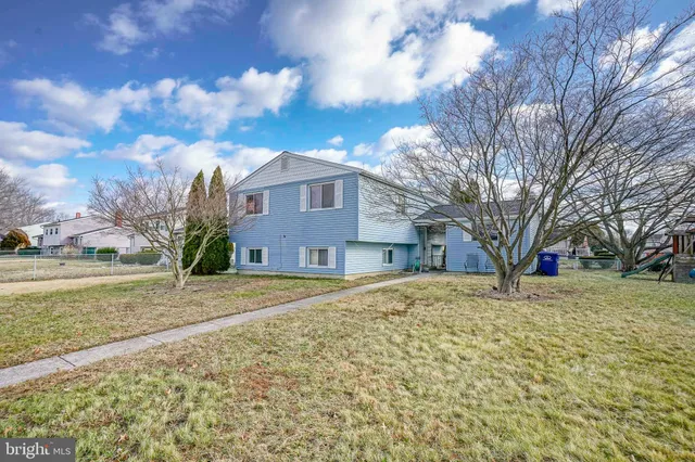 a brick house next to a yard with large trees