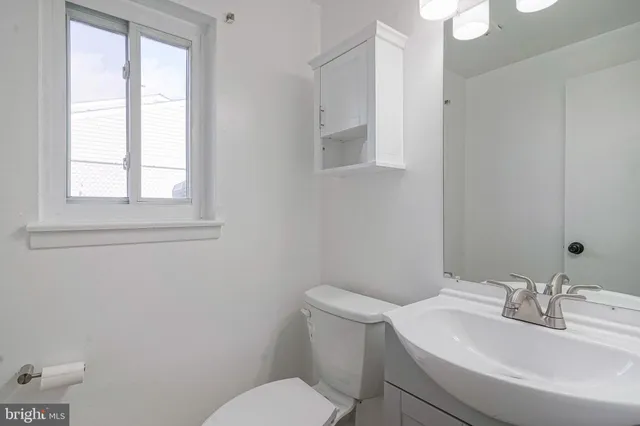 a bathroom with a toilet a sink a mirror and a window