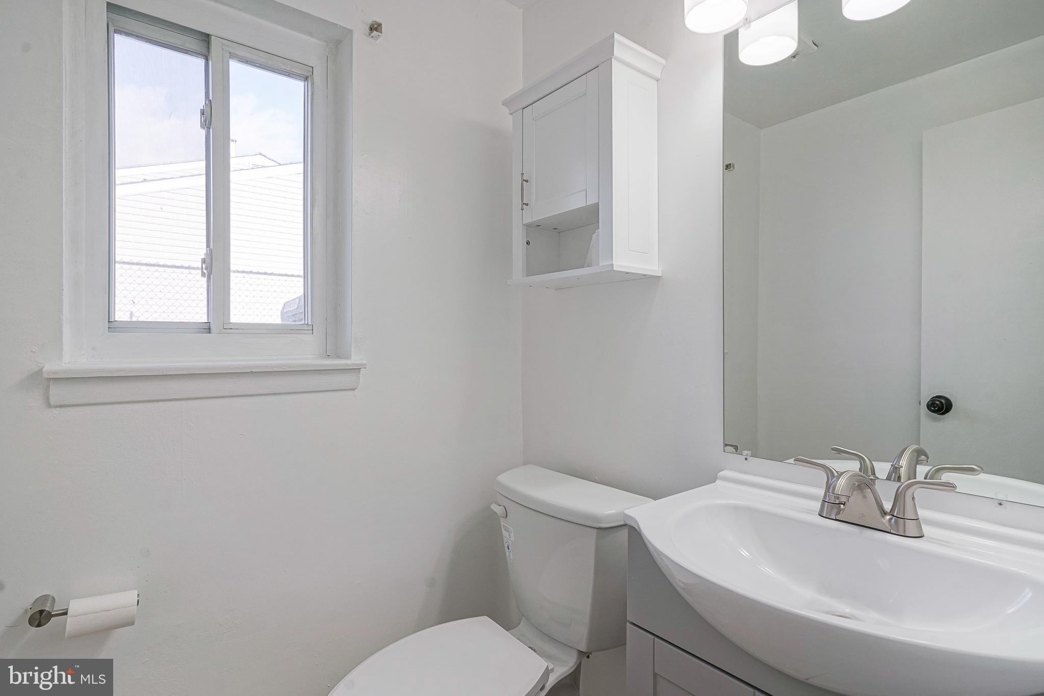 220 College Drive Pemberton, NJ 08068 - Photo 21 of 28 a bathroom with a toilet a sink a mirror and a window