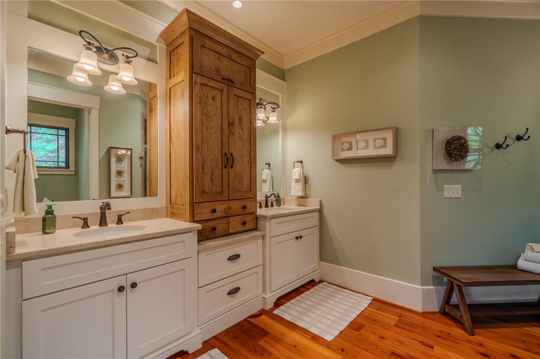 102 State Rd S-39-143 Sunset, SC 29685 - Photo 28 of 47 This primary bathroom features double vanities and natural wood flooring, creating a serene and functional space.